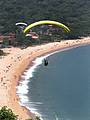 Adeptos do paraglider sobrevoam a extensa praia